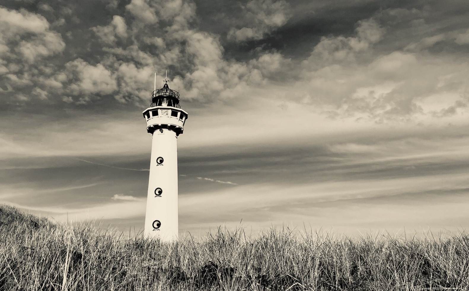Vuurtoren in de duinen onder een wolkenlucht